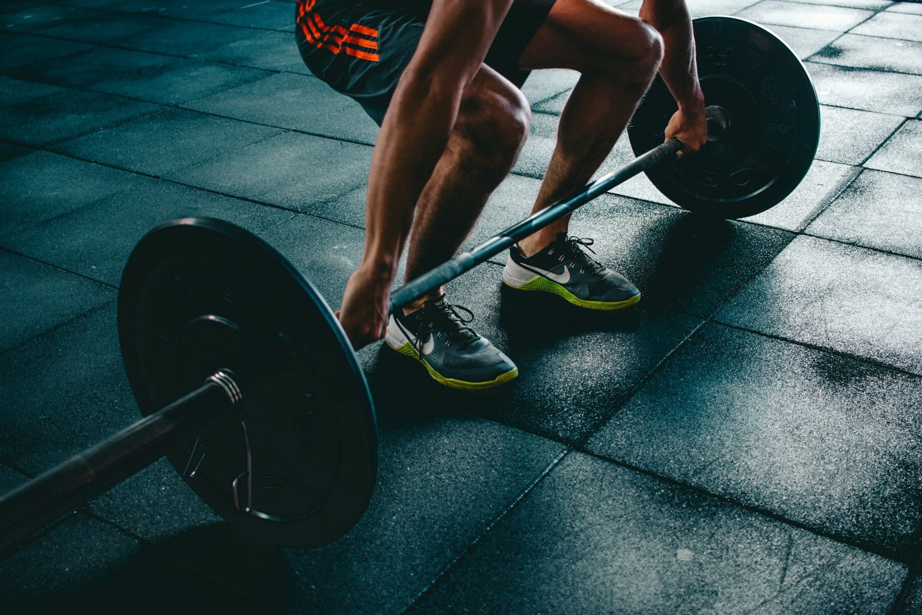 Atleta executando levantamento terra com barra olímpica em academia